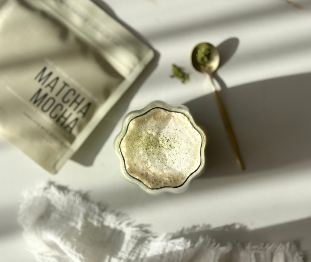 Matcha Mocha · Precision lifestyle — fluted glass matcha latte with gold spoon, soft natural light.